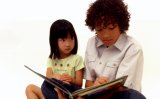 Young boy reading a story to young girl.