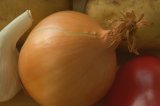 Close-up of an onion, surrounded by other vegetables.