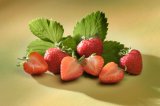 Strawberries with leaves arranged on a yellow/green background