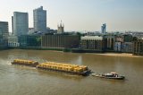 tug boat pulls barge of containers up river Thames London 