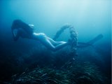 Girl swimming through a hoop at the bottom of the sea