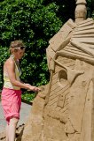 A female artist building a sand sculpture
