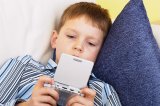 Boy on sofa playing with Gameboy