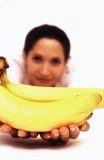 Portrait of a Hispanic female holding a bunch bananas.