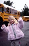A young girl dances in front of a school bus