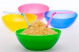 Rice and straw in green bowl in front of multi coloured empty bowls