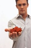 Portrait of an attractive Caucasian male holding a handful of strawberries.