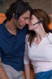 Portrait of a couple snuggling while wearing headphones and ear pieces.