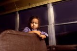 A small girl poses inside a school bus.