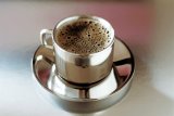 Stainless steel cup of frothy coffee