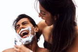 Portrait of a woman shaving a mans face while he panics.