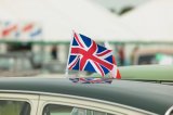 Union jack flag flying from  roof of classic english car in front of marquee at rally.