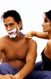 Portrait of a woman shaving a mans face.