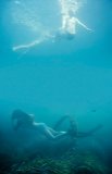 Girl swimming through a hoop at the bottom of the sea