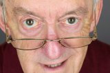 Elderly man horizontal  close up peering over glasses