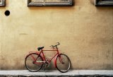 "Red Bicycle Bare Wall": a red bicycle leans against a wall in old Florence