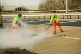 construction workers laying anti skid surface to surface of a new road