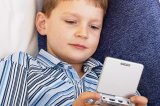 Boy on sofa playing with Gameboy
