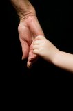 Grandfather holding Granddaughter by the hand on a black background.